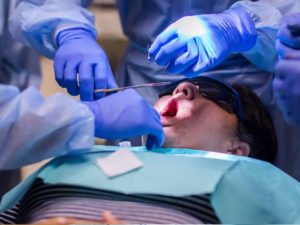 Stitching up Patient After Implant Surgery